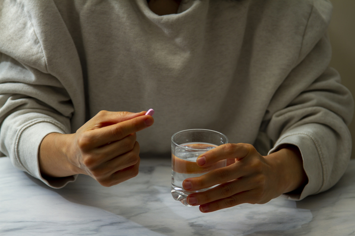 woman taking a pill with water