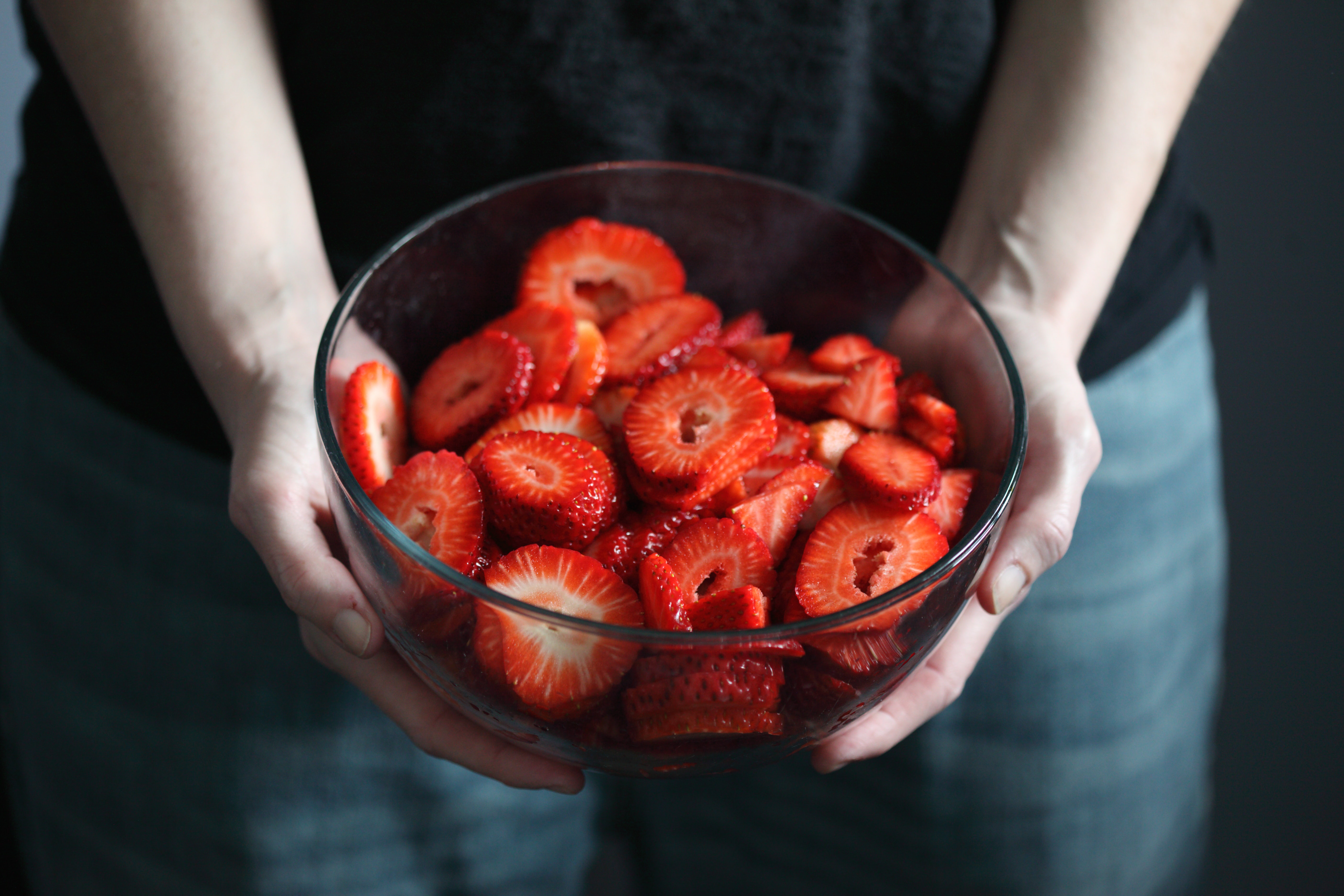 woman holding a bowl of sliced strawberries