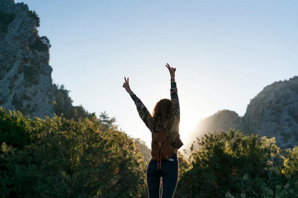 woman in nature liftering her arms to the sky