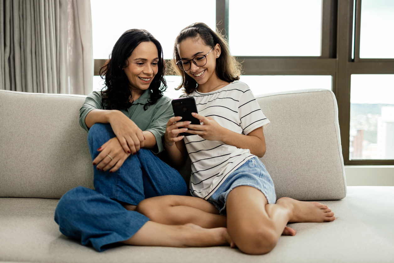 mom and daughter laughing at something on a mobile phone