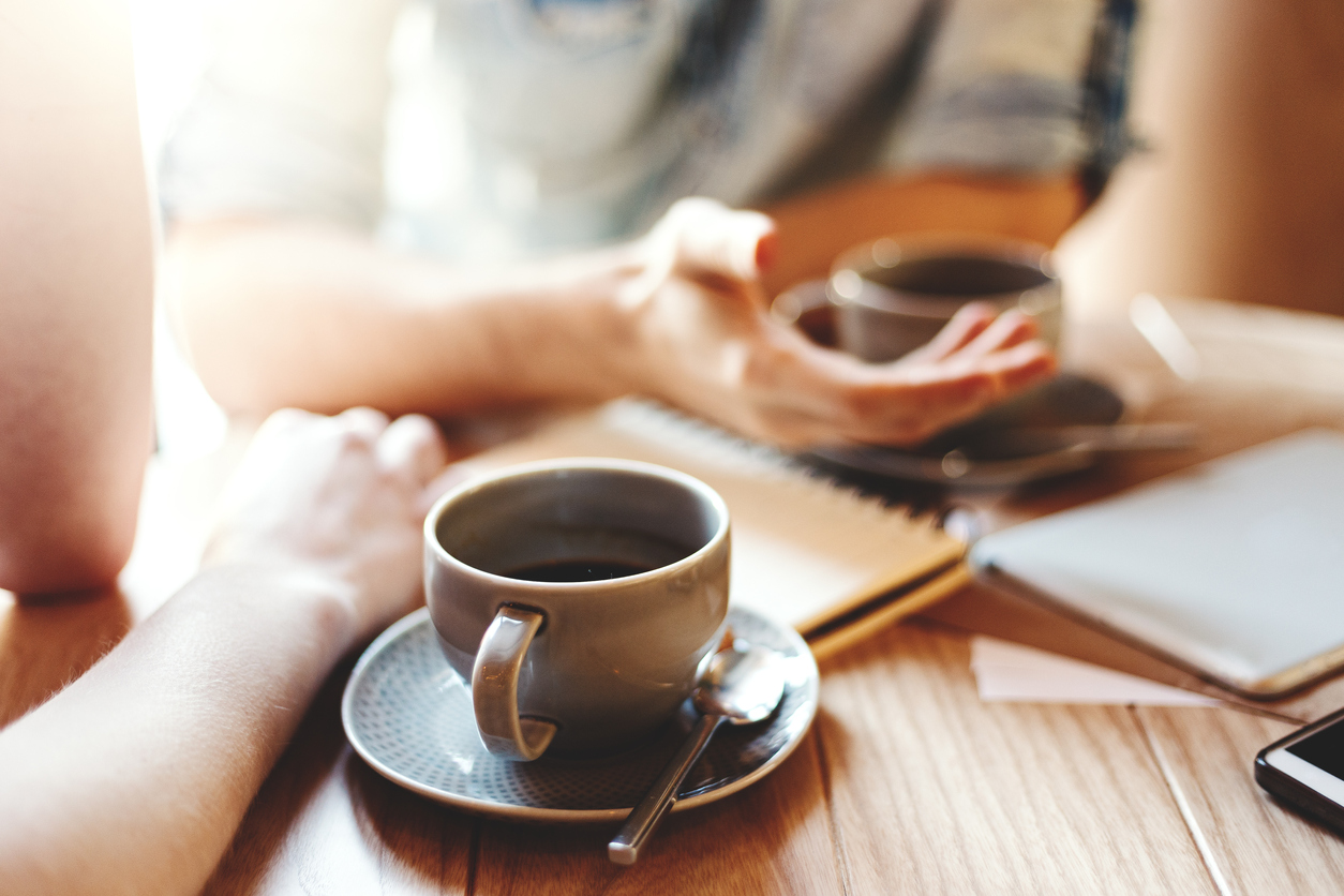 two people conversing over coffee