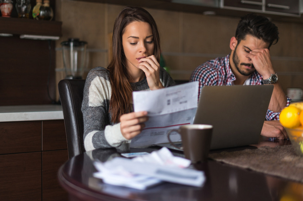 couple looking at fertility bills with frustration and worry on their faces