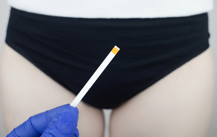 doctor holding a vaginal infection test strip near a woman's vulva