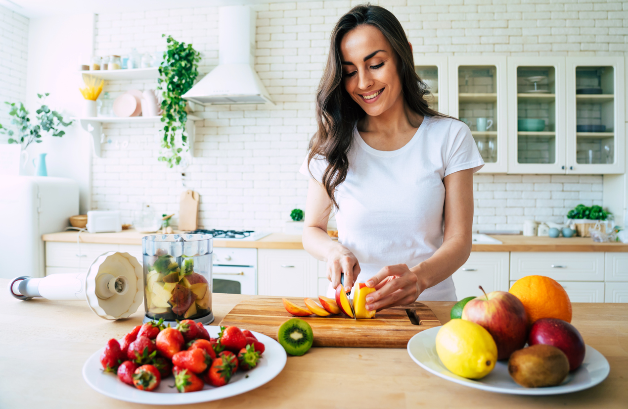 woman slicing fresh fruit for a smoothie