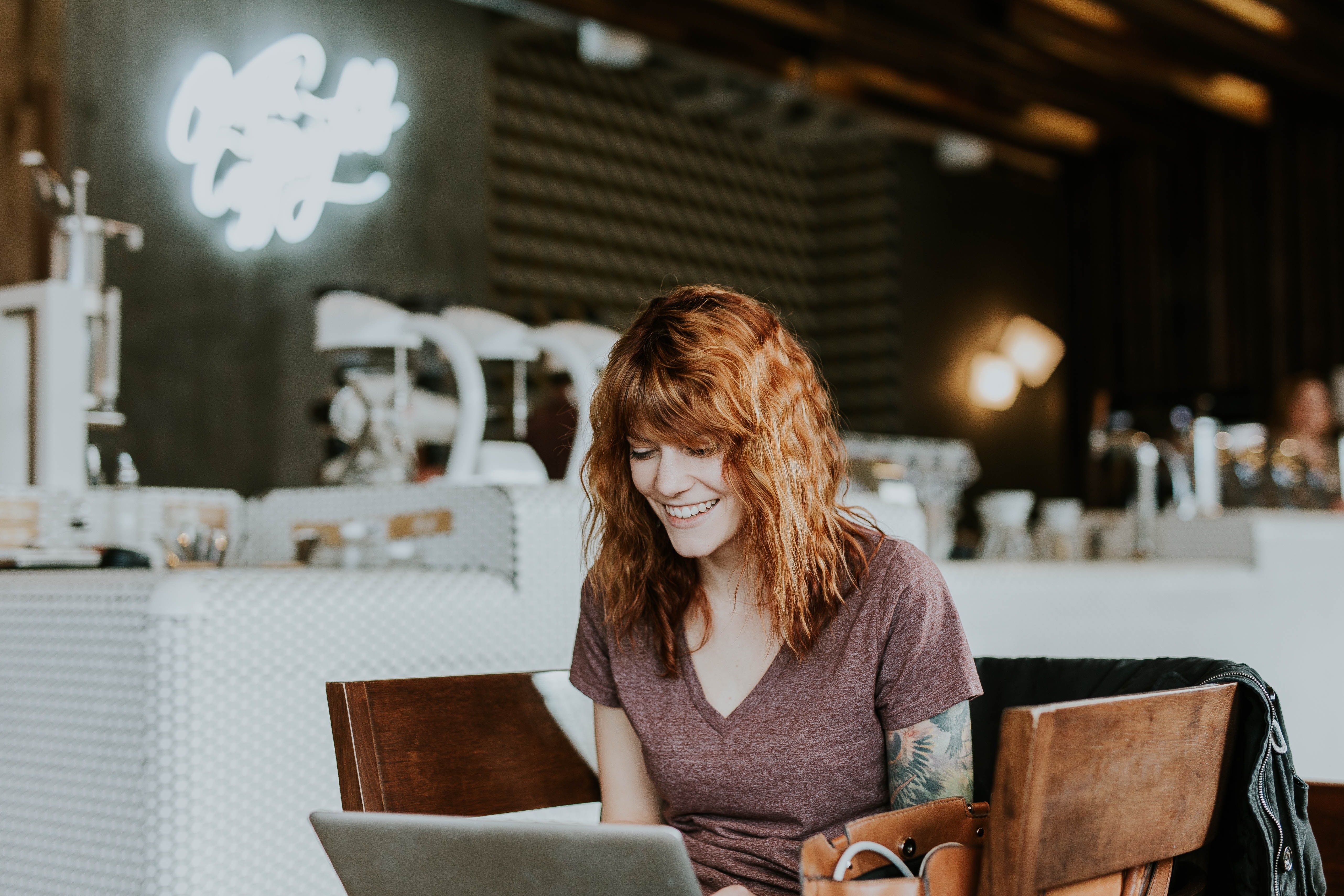 woman smiling as she reads article on her laptop