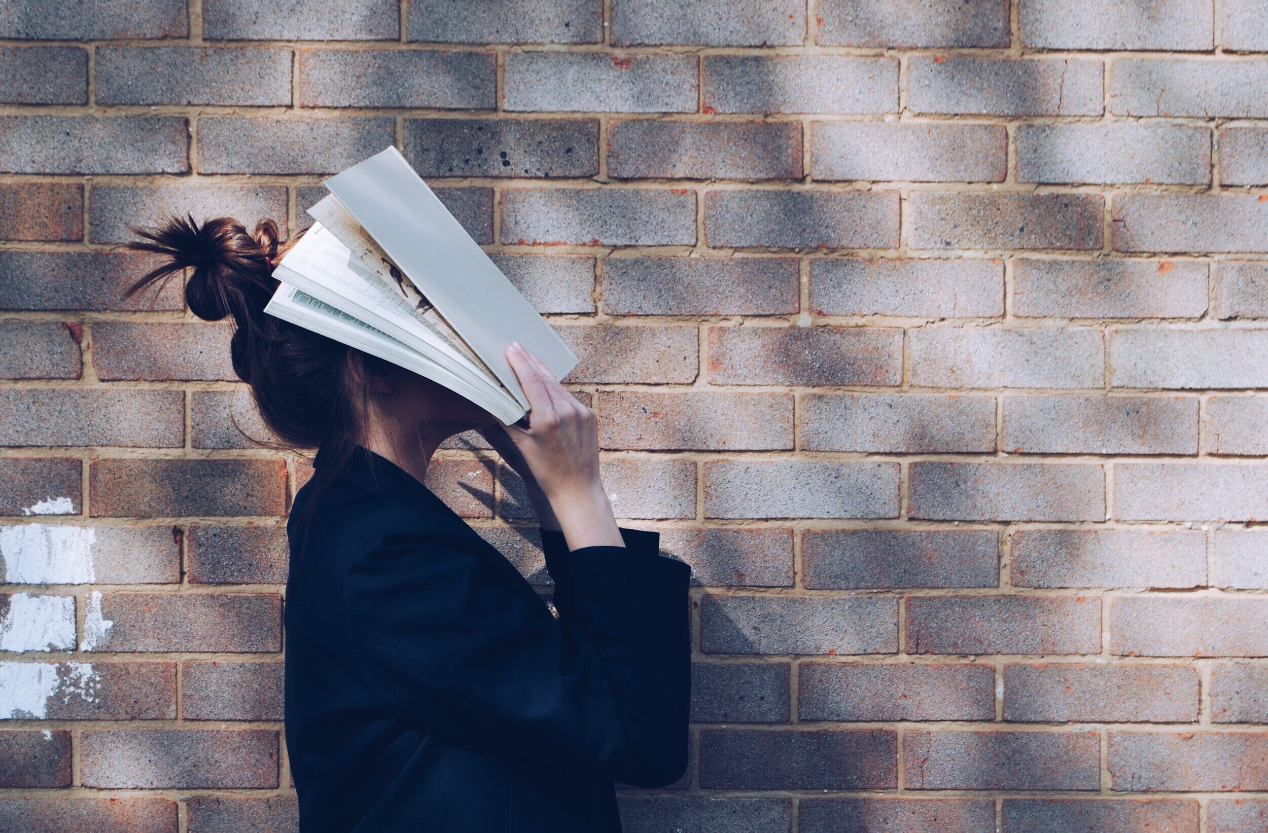 ; woman lifting book to her face