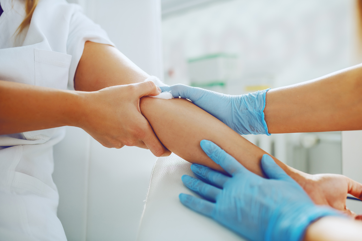 woman applying pressure to arm after having her blood drawn