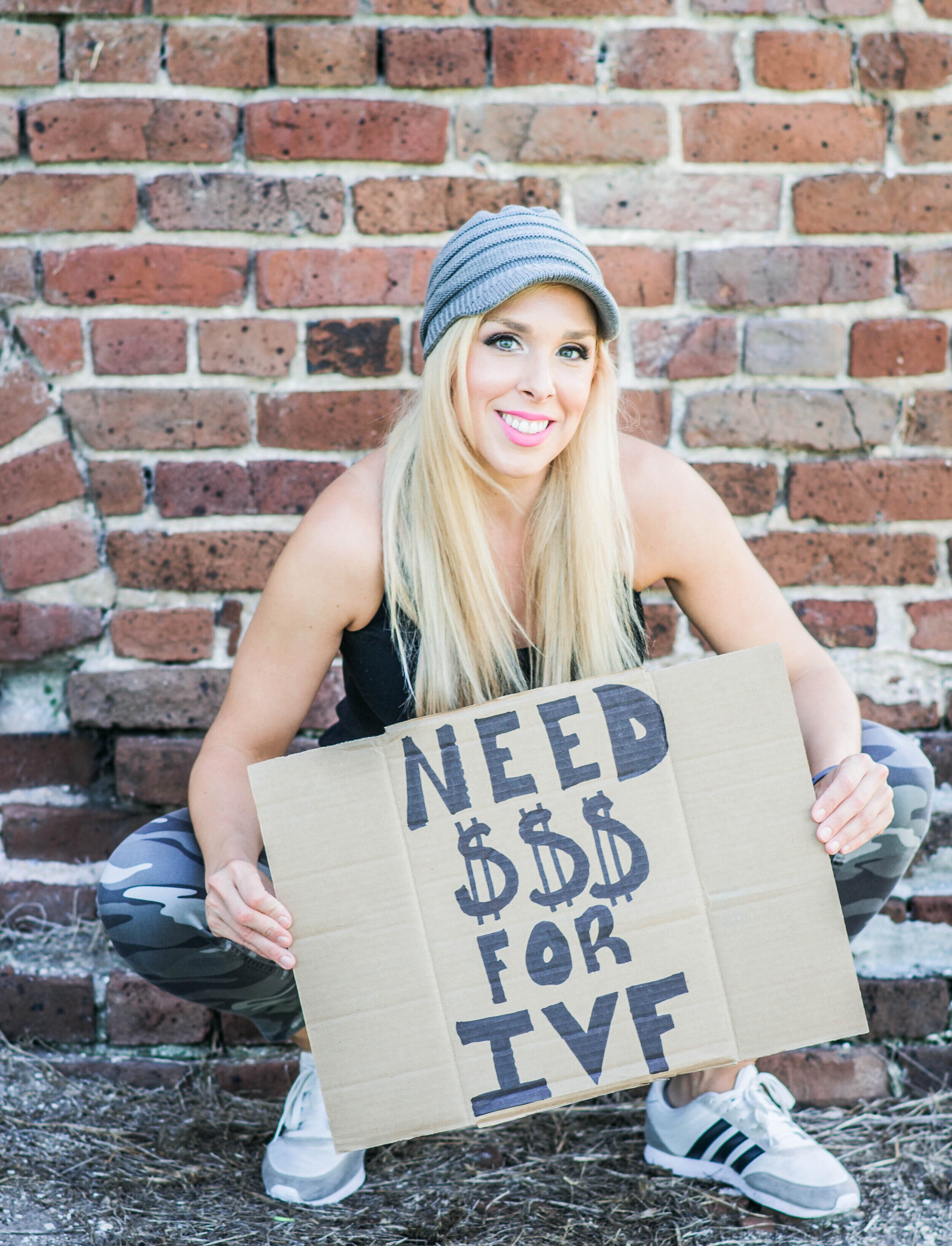 fertility finance coach devon baeza holding a cardboard sign