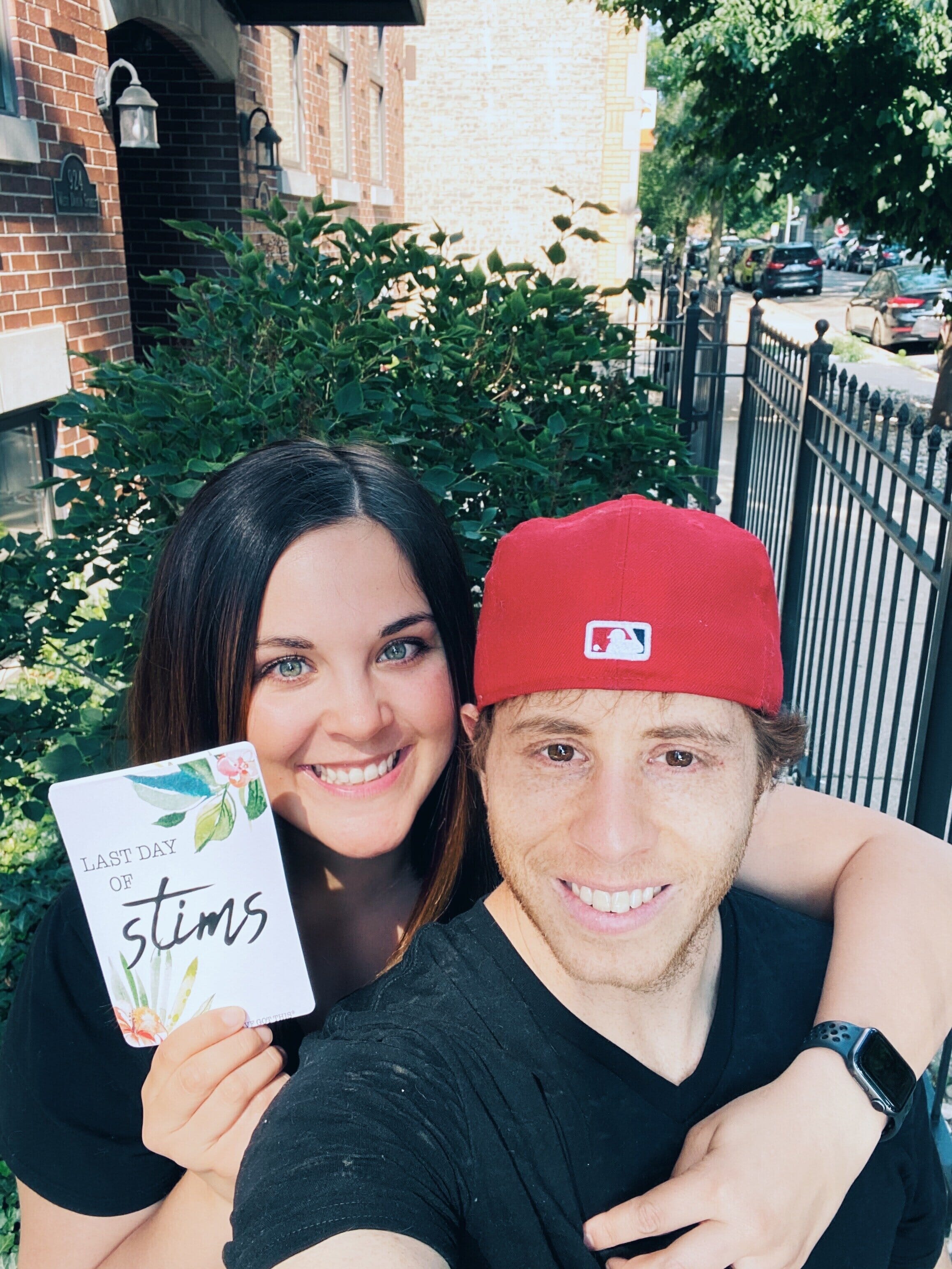 taylor ortiz and husband with a sign that reads "last day of stims"