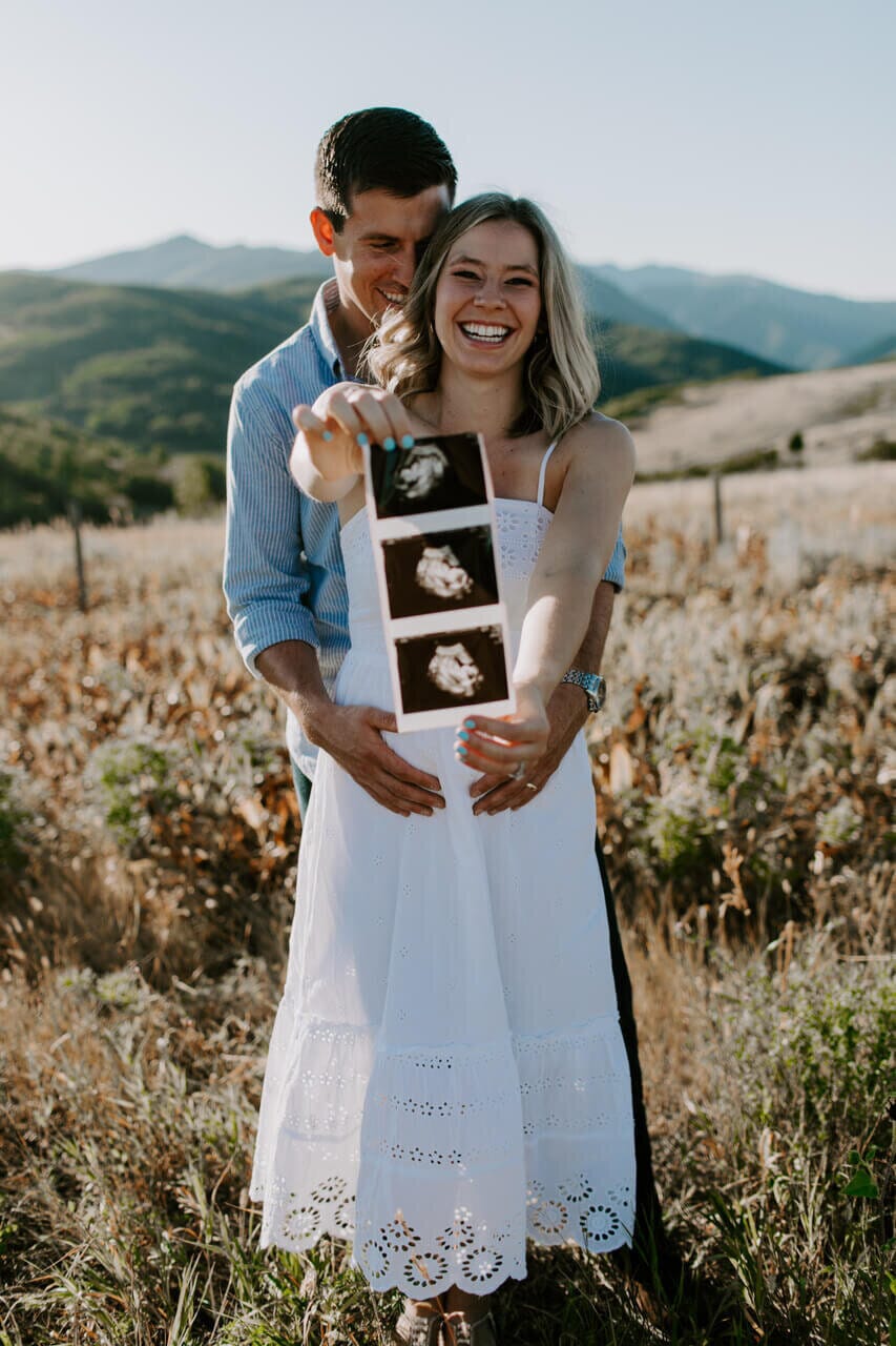 infertility warrior jen lowell and her husband holding ultrasound pictures of their child