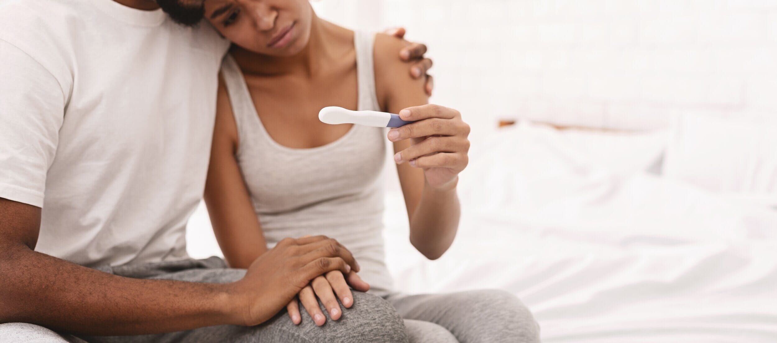 couple looking sadly at a negative pregnancy test