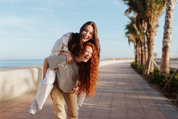 two women piggybacking at the beach