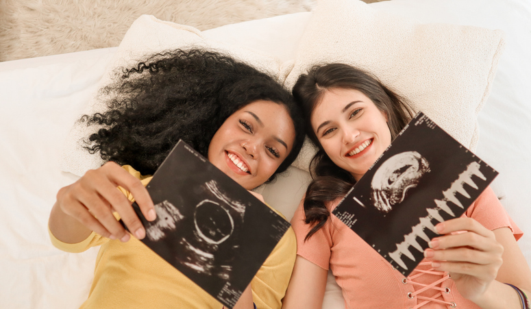 two women holding up sonograms