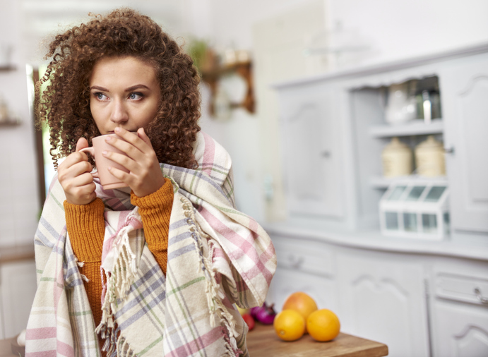 woman wrapped in a shawl drinking hot tea