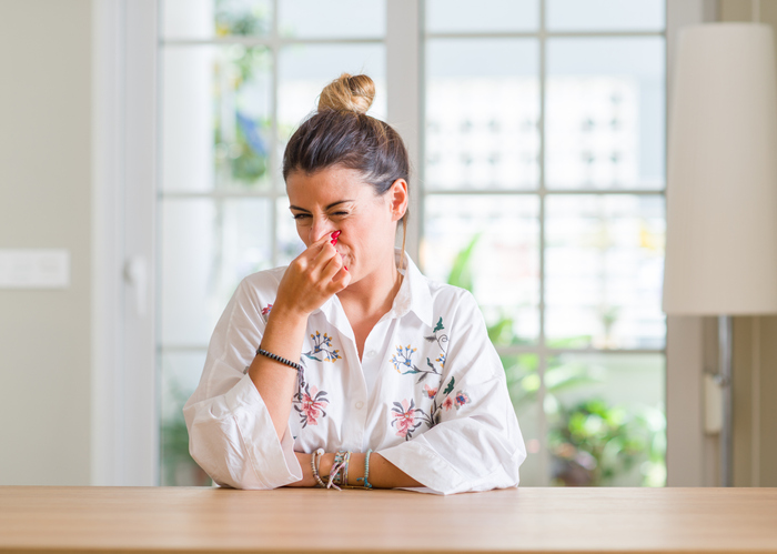woman holding her nose due to a foul odor