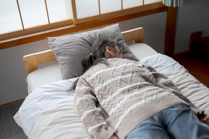 young woman lying face down on her dorm bed