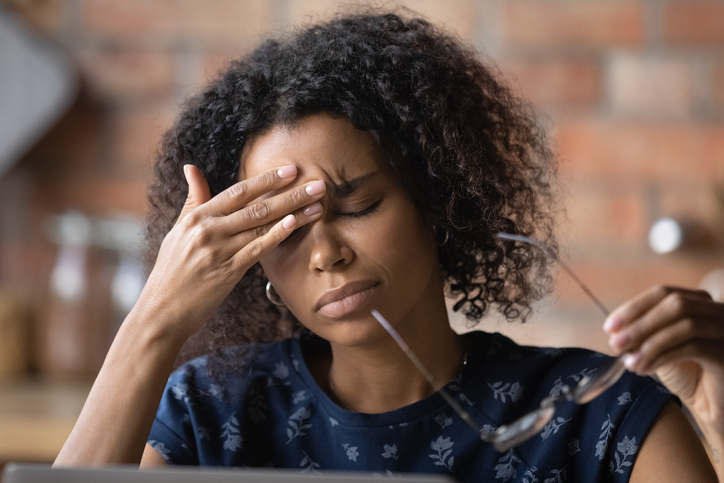 woman with migraine rubbing her forehead