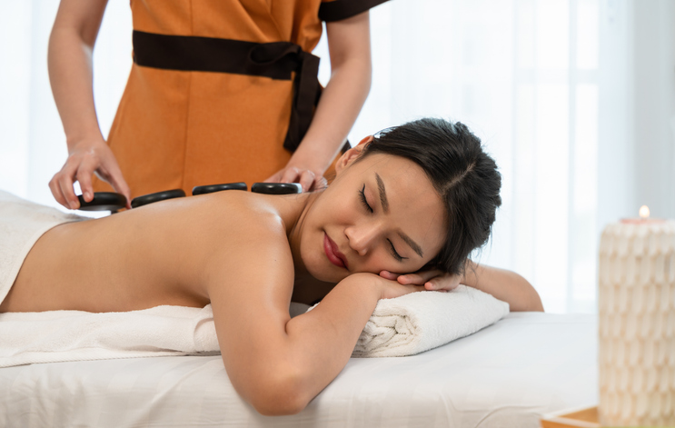 masseuse placing hot stones on a client