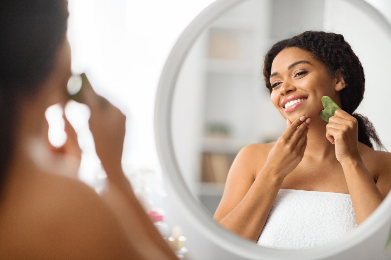 woman doing gua sha in the mirror
