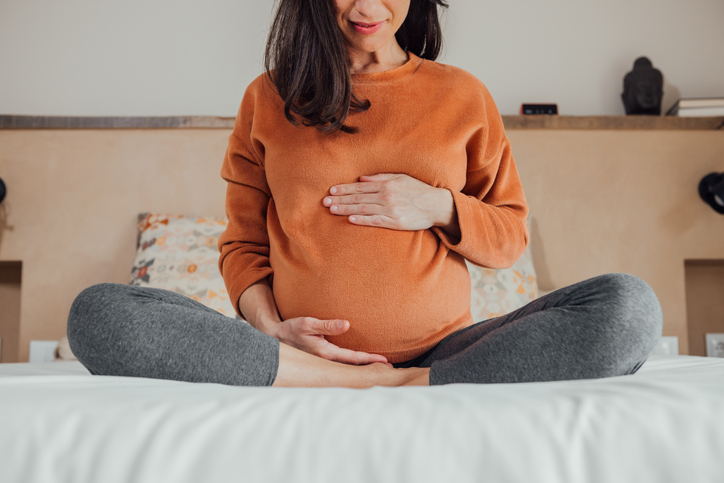 pregnant woman sitting cross-legged cradling her belly