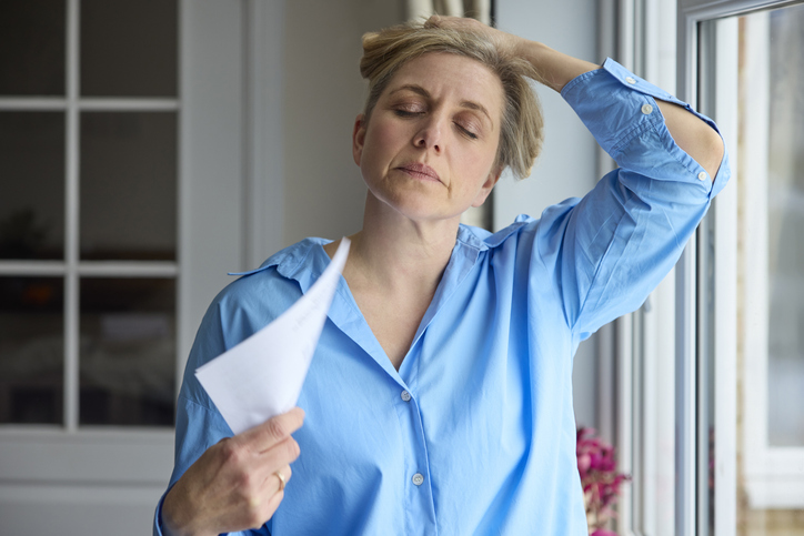 perimenopausal woman fanning herself during a hot flash