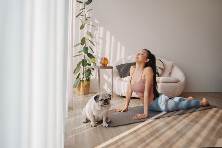 woman doing yoga on a mat near her dog