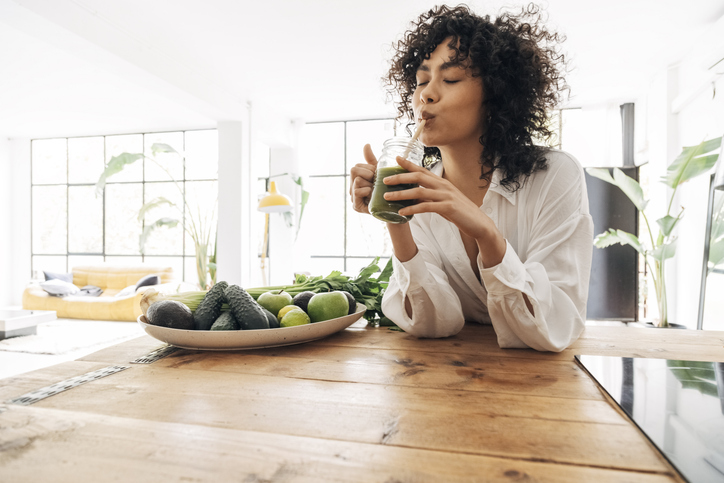 woman sipping on a green smoothie
