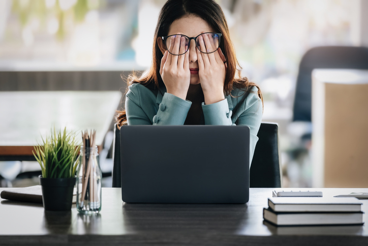 woman with high-functioning depression rubbing her eyes at work