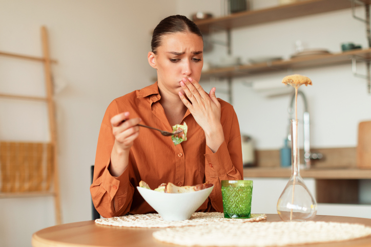 woman feeling norovirus coming on as she eats a salad