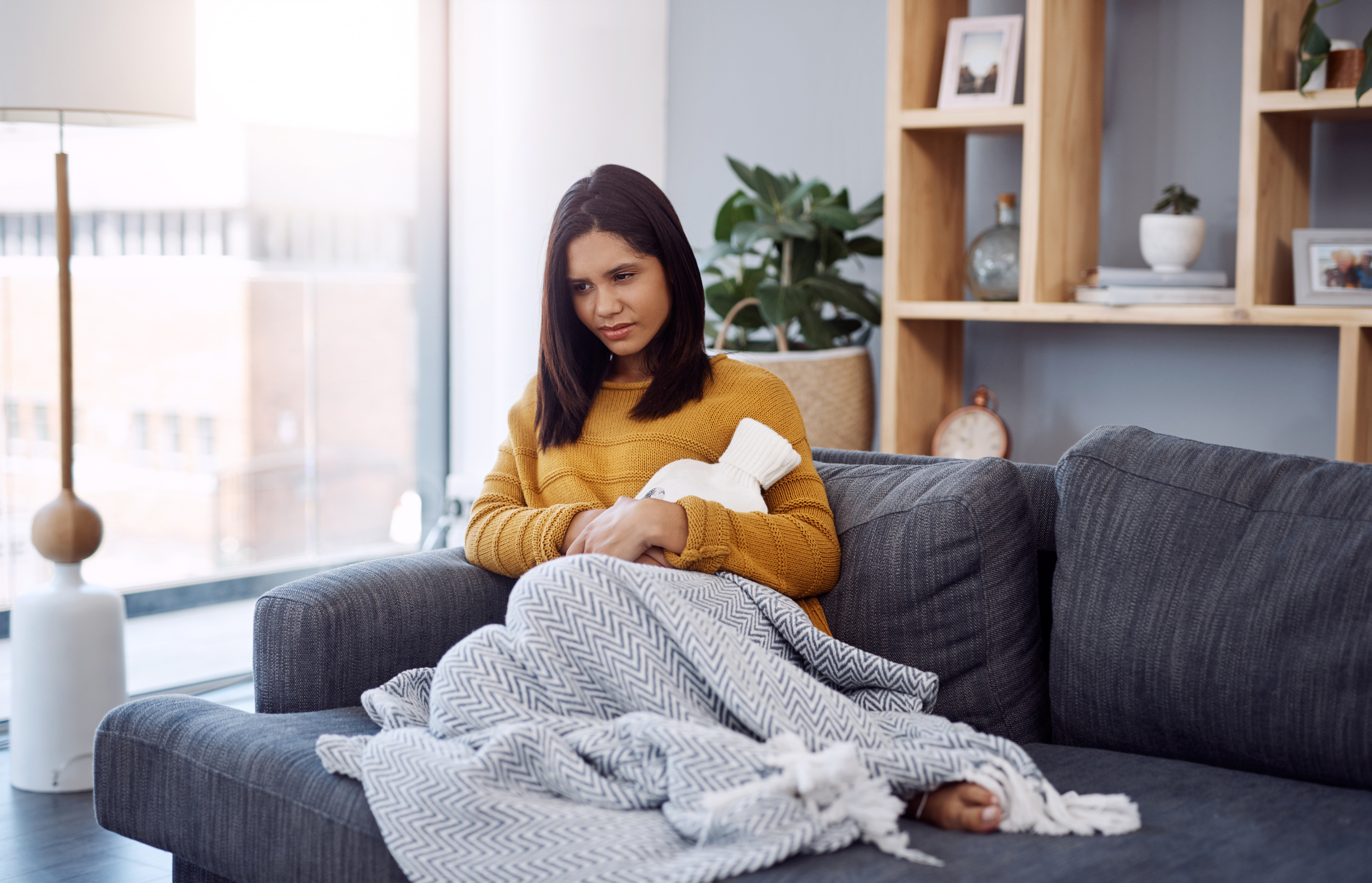 woman in pain on the sofa due to period diarrhea