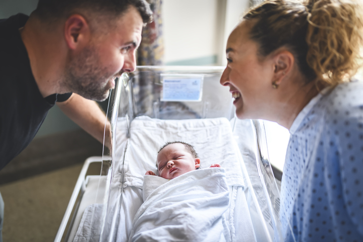 couple looking at their newborn baby in a hospital bassinet