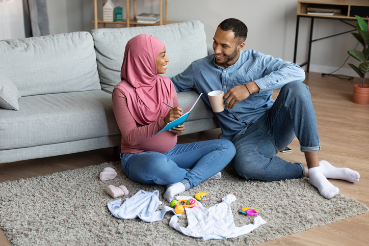 pregnant couple writing a to-do list to prepare for baby