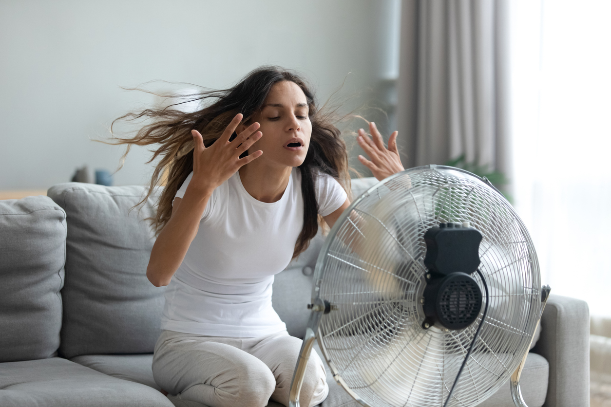 woman sitting in front of the fan during a hormonal hot flash