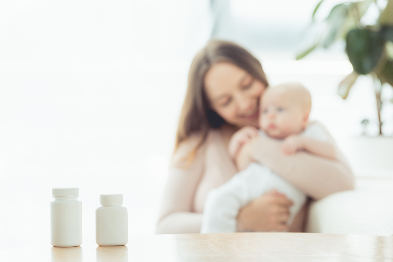 prenatal vitamin bottles near a mom and her newborn baby