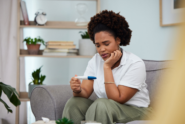 woman looking at pregnancy test and wondering how soon after embryo transfer can you test