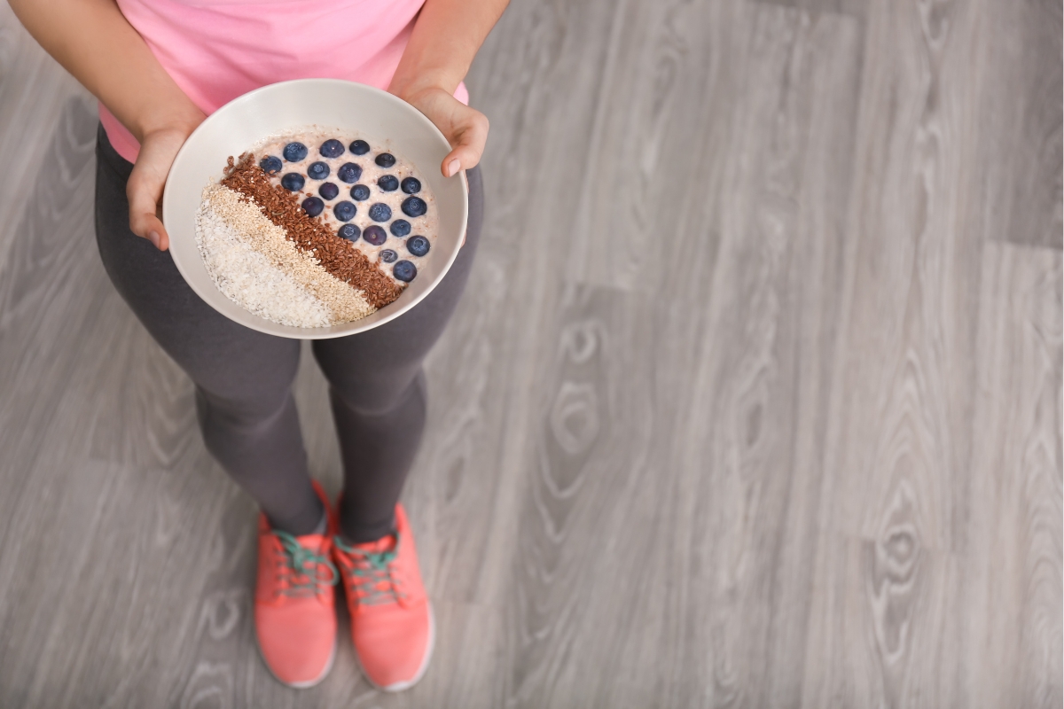 woman with a bowl of yogurt, blueberries, and seeds