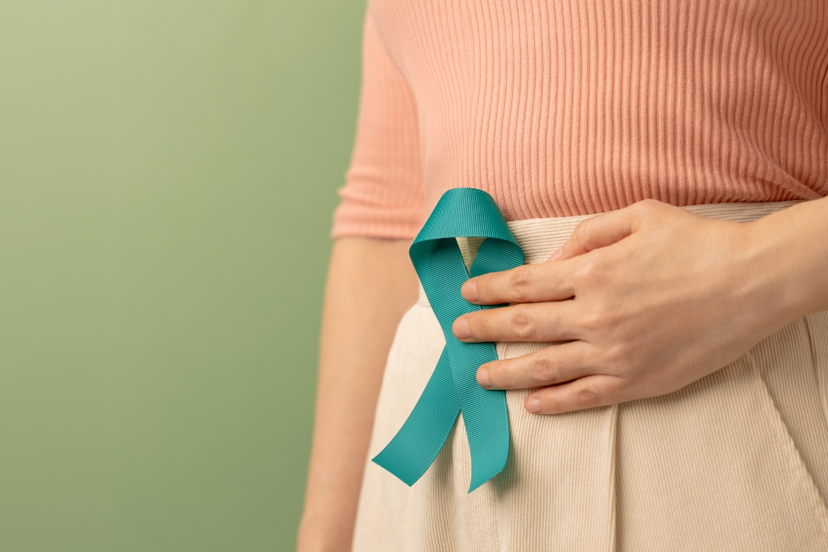 woman holding a teal ribbon near her ovaries