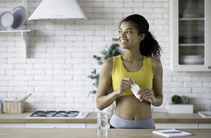 woman opening a supplement bottle post workout
