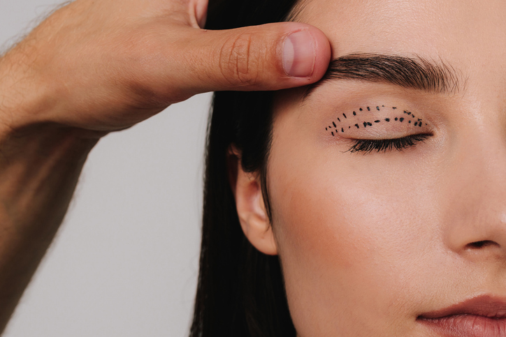 plastic surgeon lifting a woman's eyelid before blepharoplasty