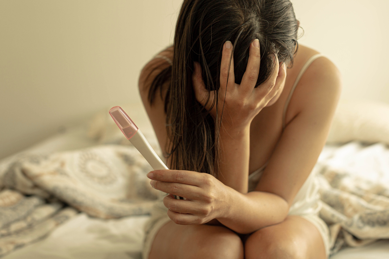 devastated woman holding a negative pregnancy test