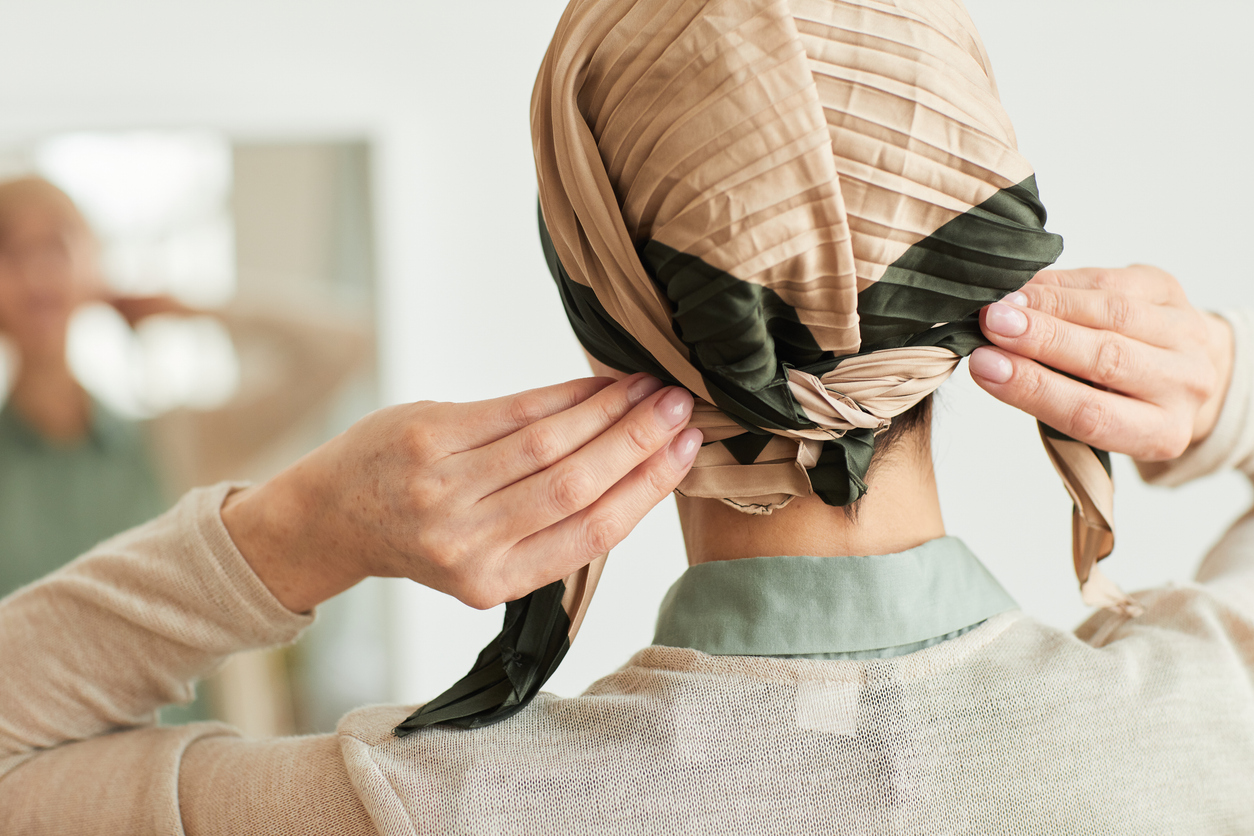 woman with cancer adjusting her head scarf