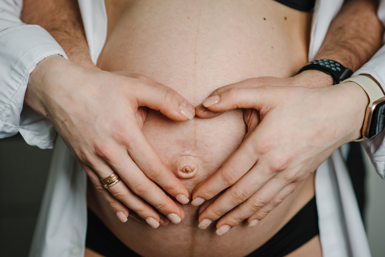 couple cradling woman with a pregnancy belly line