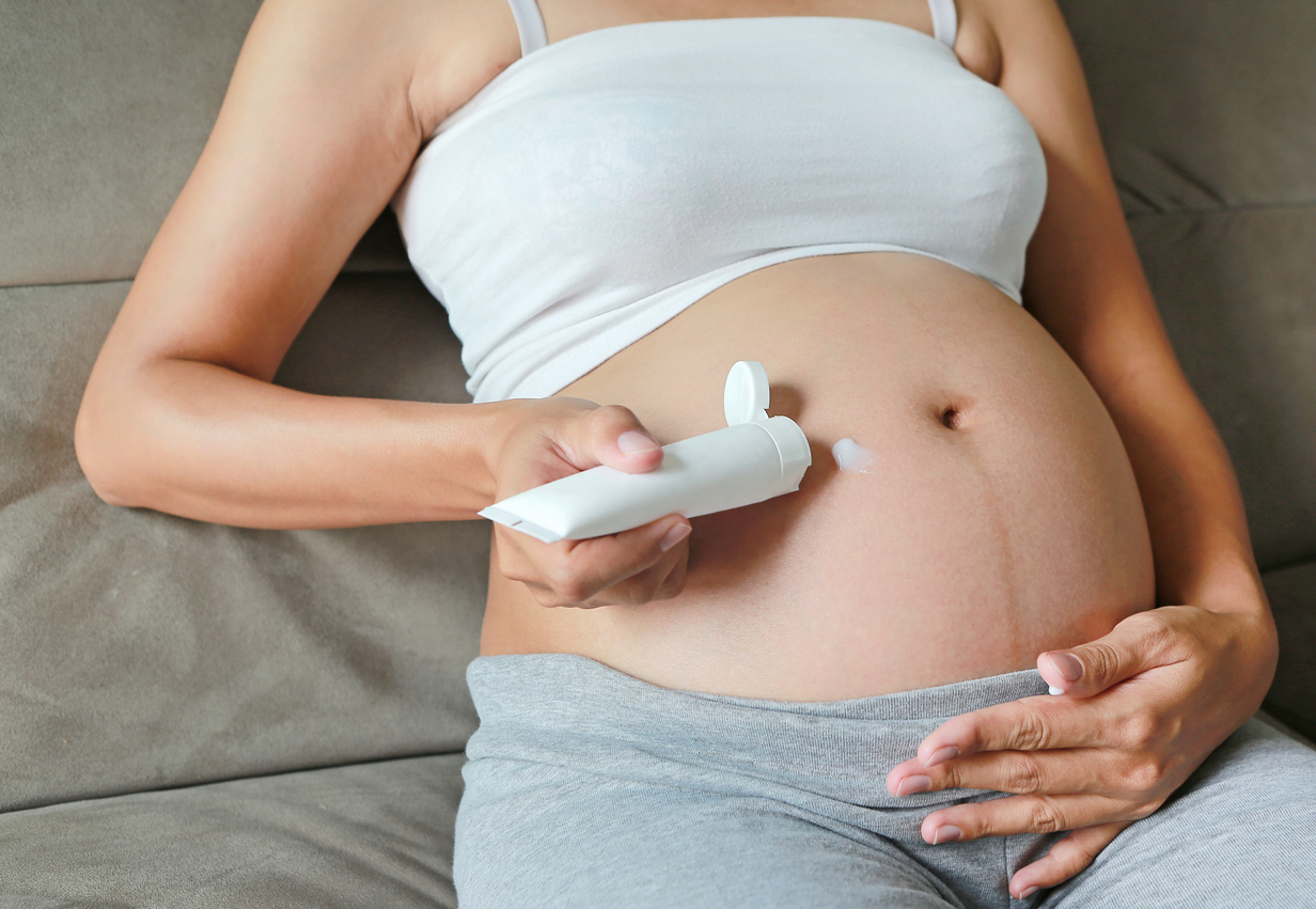 woman putting cream on her pregnant belly