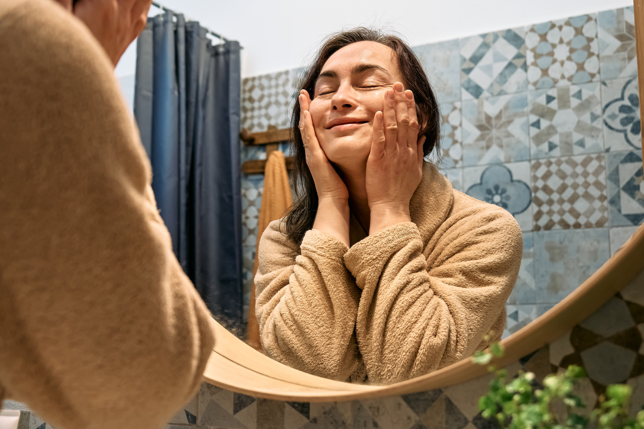 woman smoothing her skin and smiling