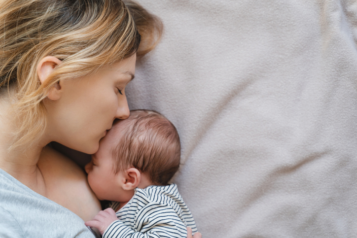 woman over 40 kissing her newborn baby