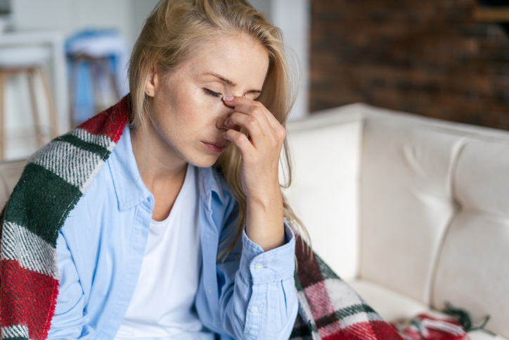 woman pinching her nose to relieve headache pain
