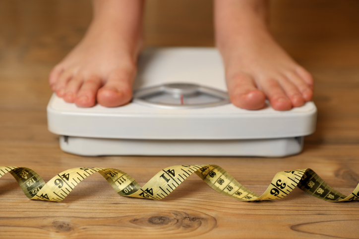 woman on a scale measuring tape at her feet