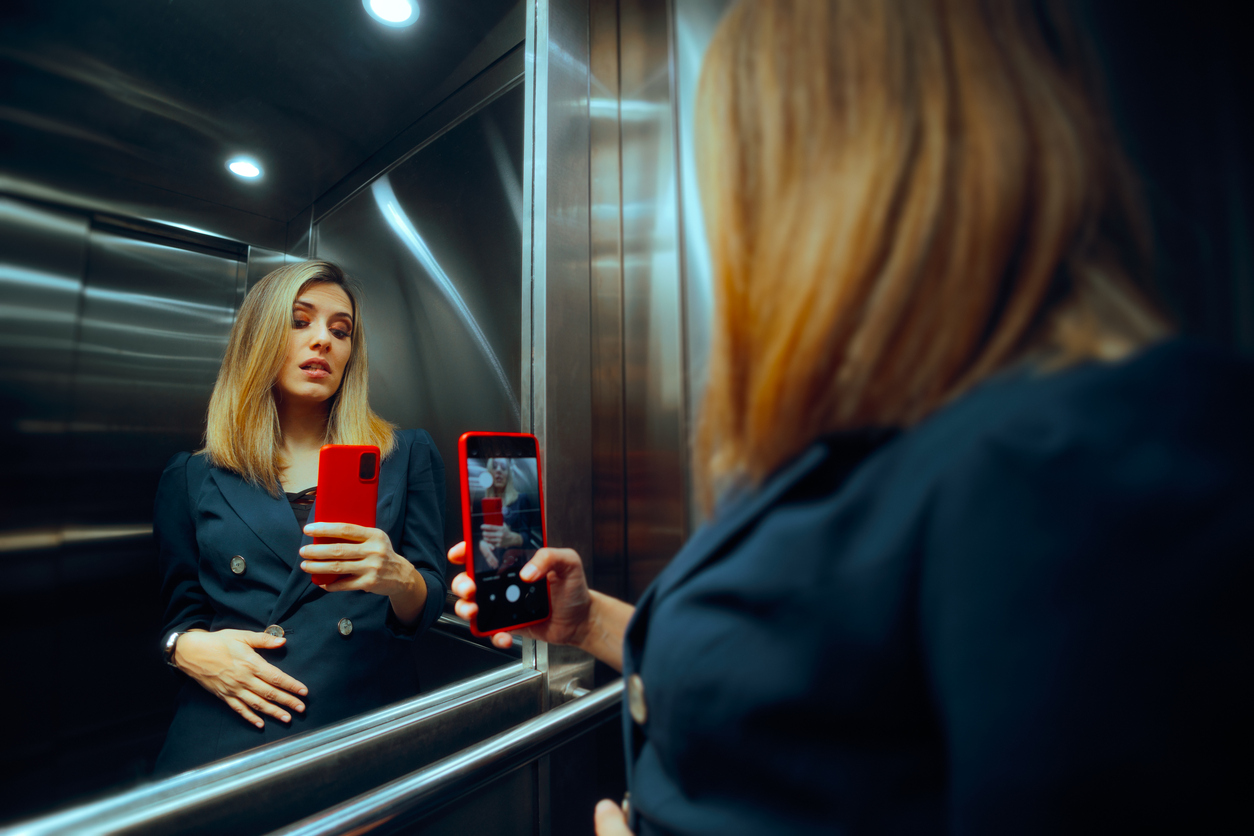 woman evaluating herself in an elevator mirror