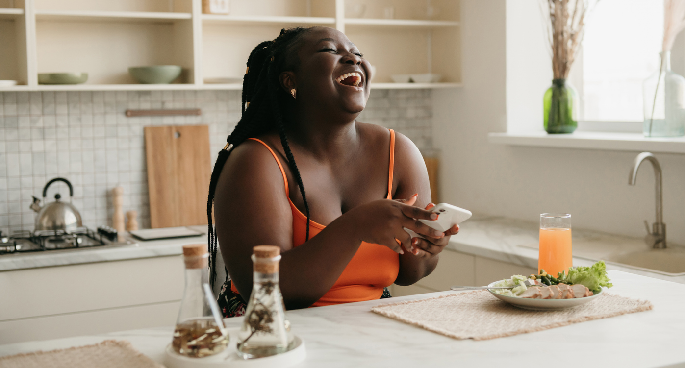 woman laughing while eating a healthy meal