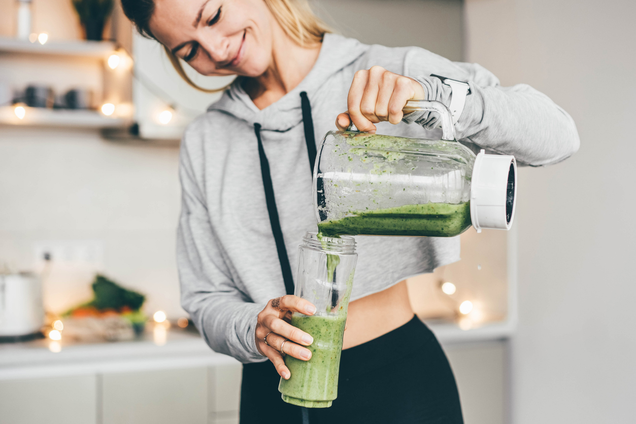 woman pouring a green smoothie